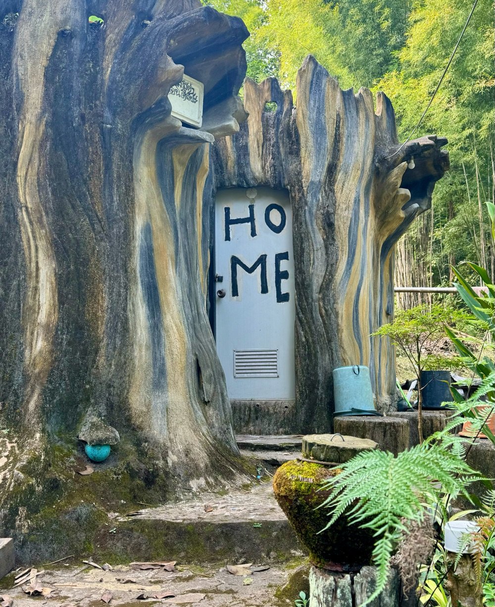 a small Thai house with 'HOME' painted sloppily on the front door