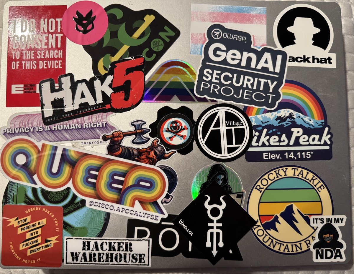 Laptop covered with cybersecurity, hacking, and activist stickers including OWASP, Hack5, mountain-themed logos, and anti-surveillance messaging.