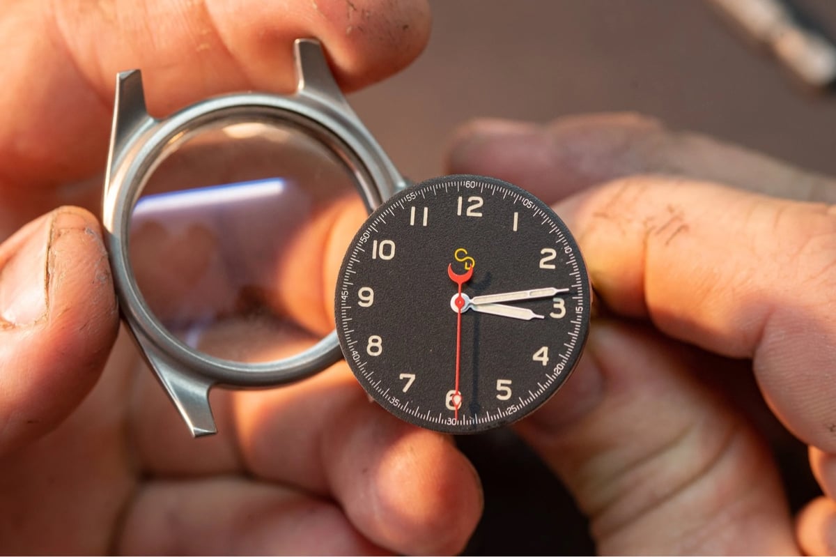 a man holds two pieces of a watch