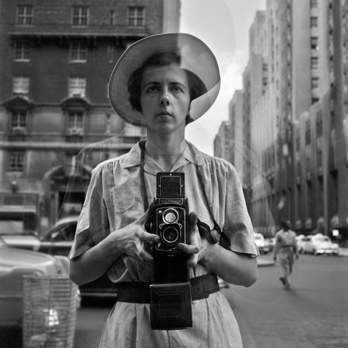 black & white self portrait of Vivian Maier reflected in a store window