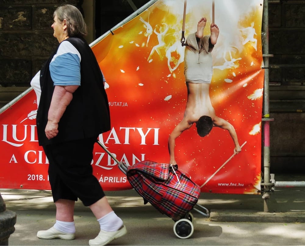 a woman walks in front of an advertisement where it appears a person is taking something from her cart