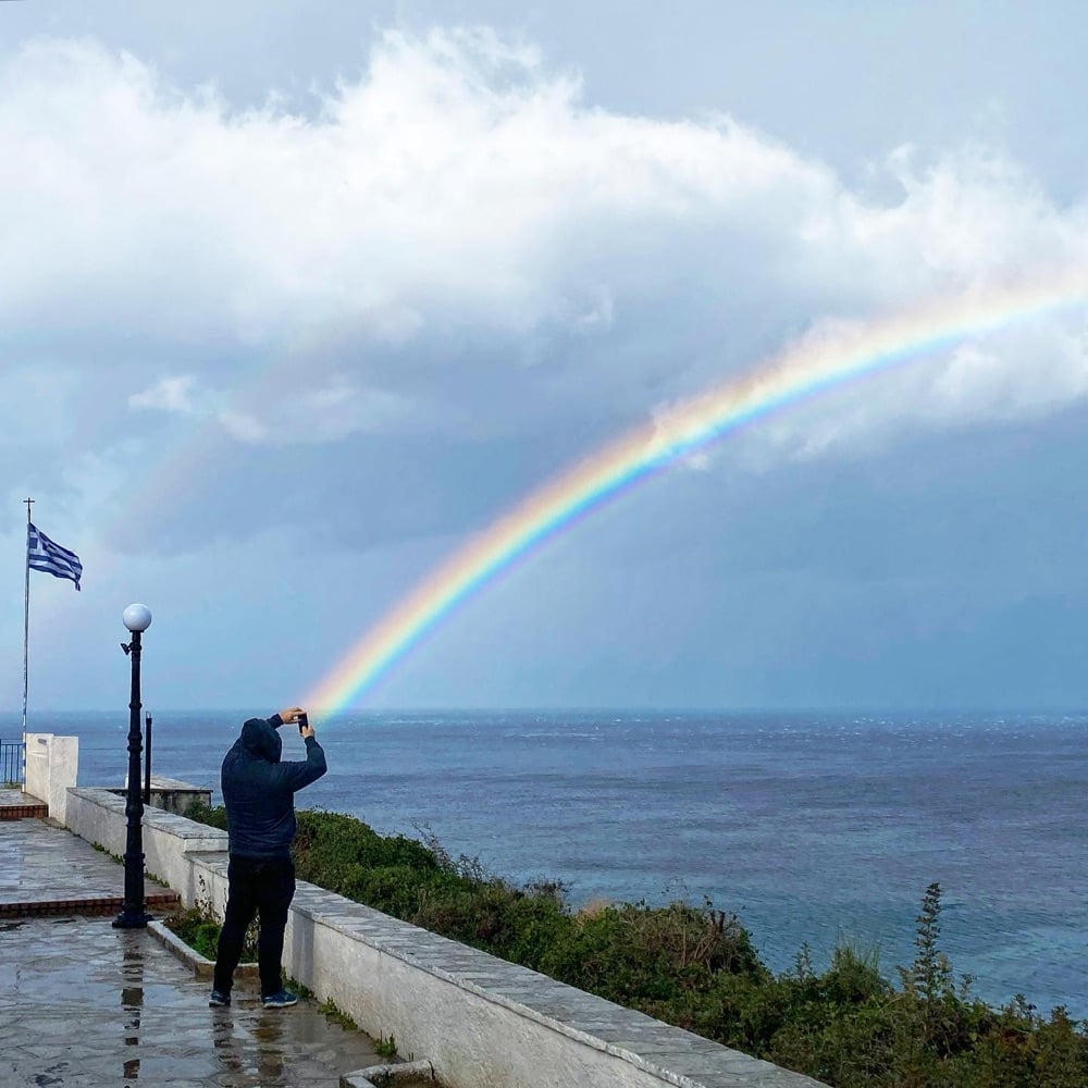 a rainbow appears to emanate from a photographer's camera