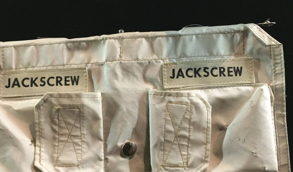 a portion of an Apollo 11 spacesuit with two pockets labeled 'jackscrew'