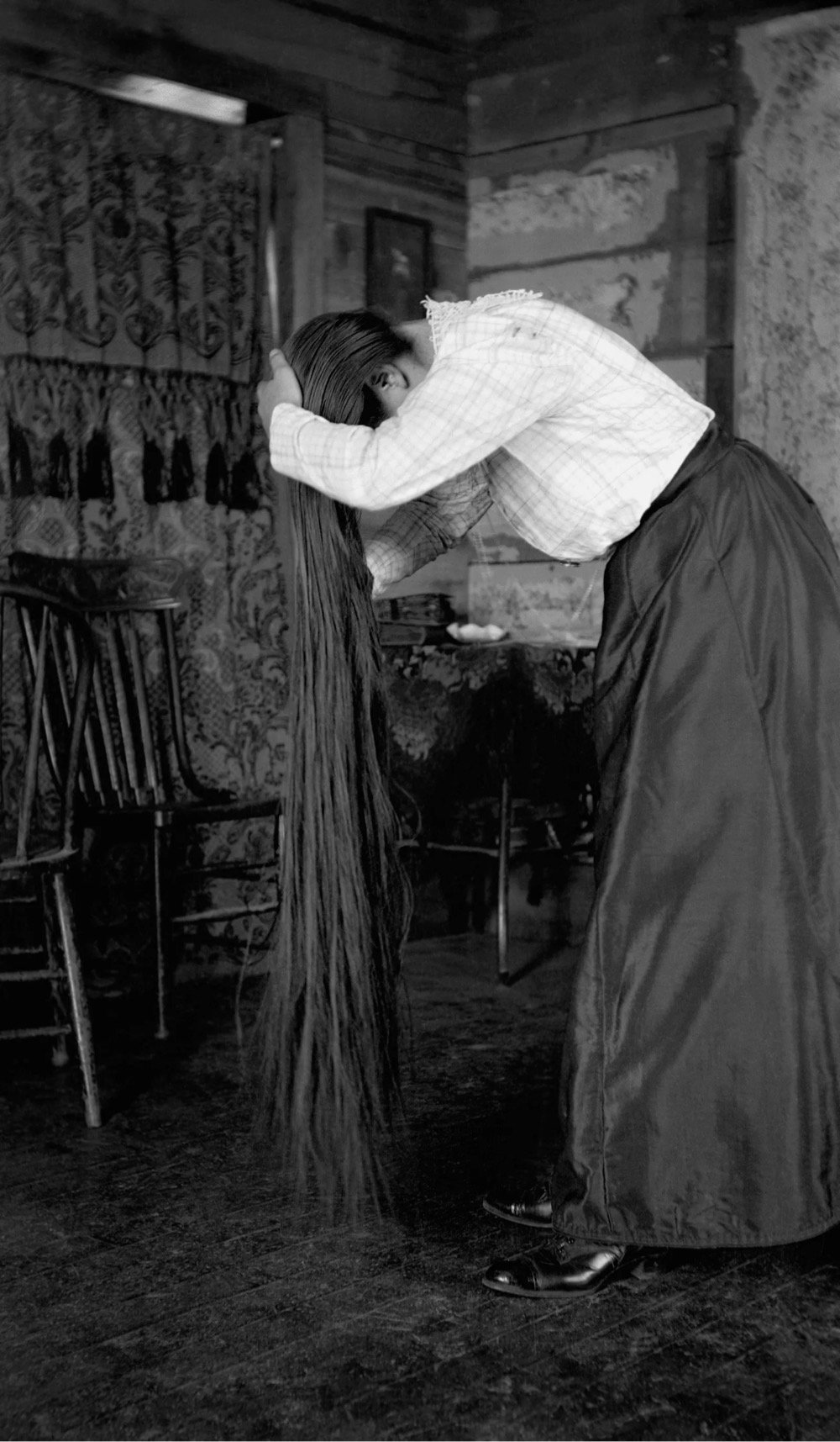 a woman with very long hair bends over to show it off