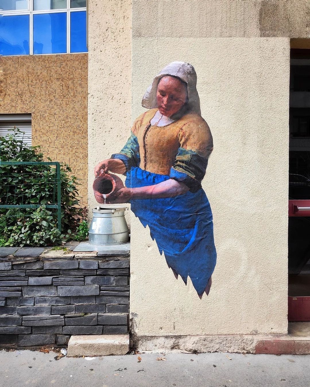 street art of Vermeer's Milkmaid pouring water into an actual jug