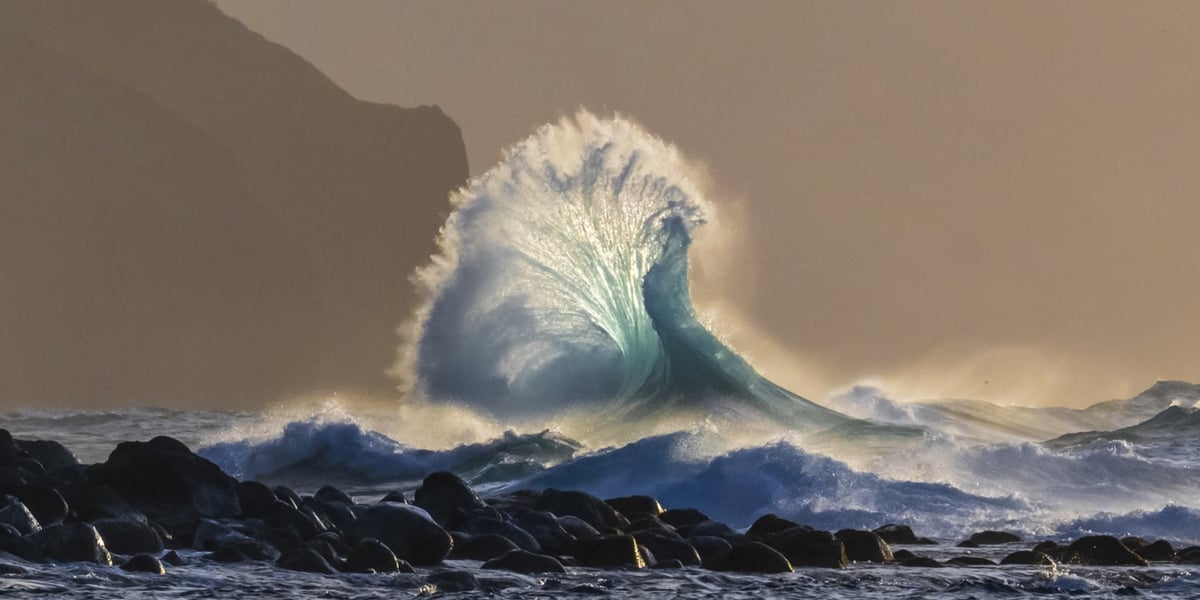 a wave crashes on rocks