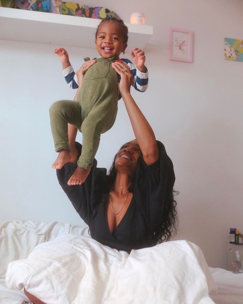 a woman raises a smiling child in the air