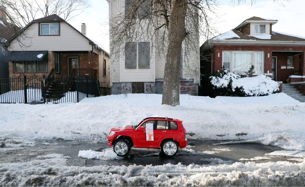 a toy car parked in a shoveled-out parking spot