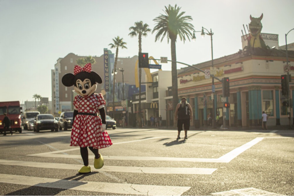 a person in a Minnie Mouse costume walking across the street